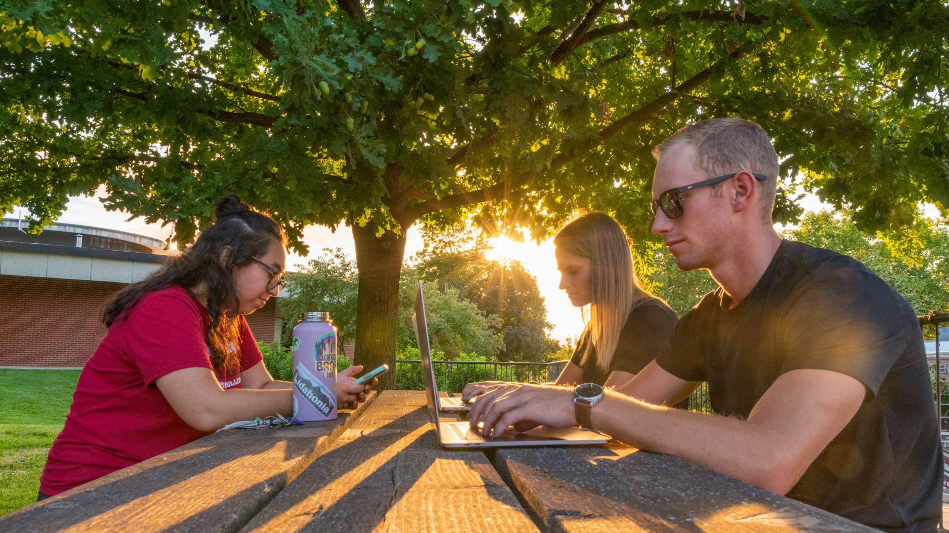 Students writing at a picnic table